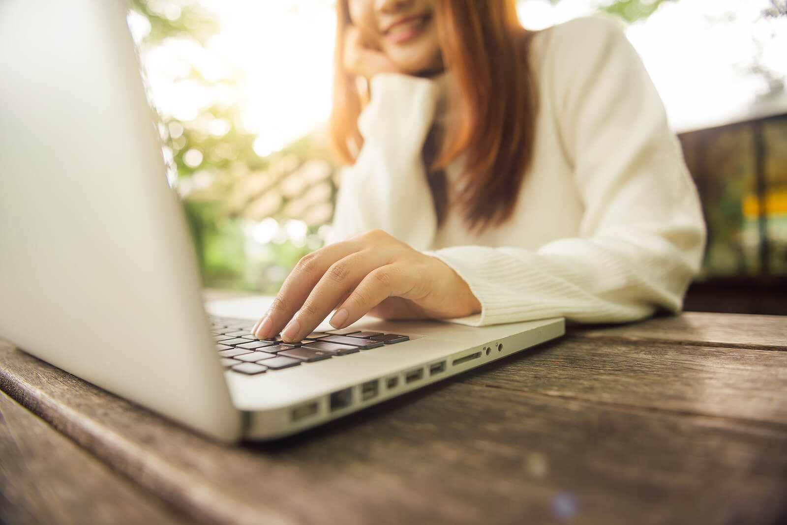 A woman smiles as she types on her laptop at a park table. Online therapy in Seattle, WA can happen from where you are most comfortable. Learn more about online LGBTQ therapy in Seattle, WA and other services including online EMDR in Seattle, WA.