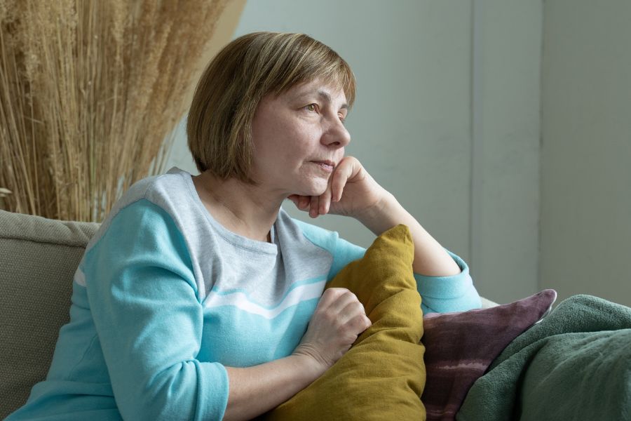 A woman sitting on a couch stares with a blank expression. This could represent being lost in traumatic thoughts that an EMDR therapist in Seattle, WA can help you address. Learn about the benefits of EMDR therapy in Seattle, WA, and overcome past trauma today.