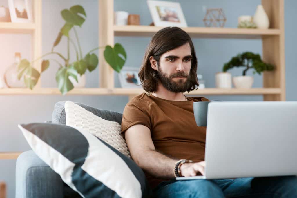 Adult male engaging in online therapy  on a sofa in his living room