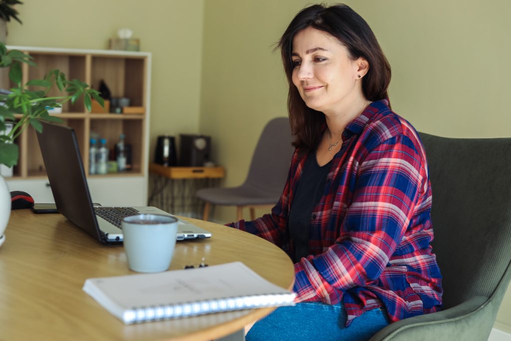 brown-haired woman in plaid shirt getting ready for their online therapy session 