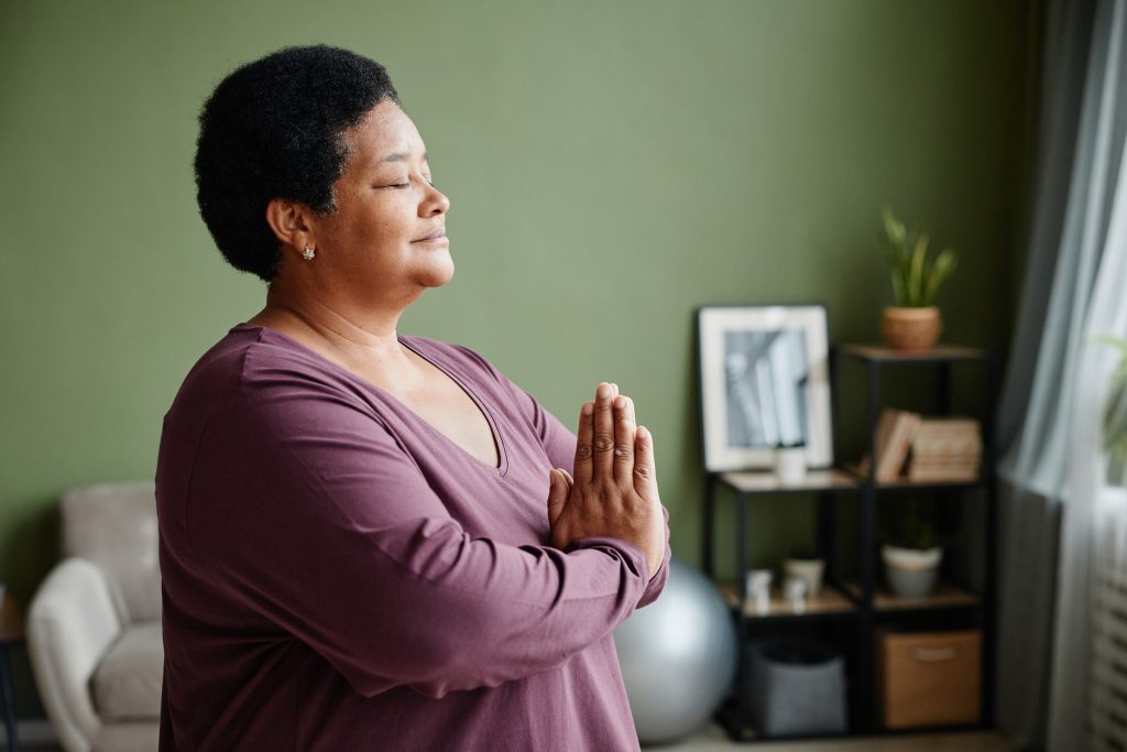 Side view of a woman meditating at home with eyes closed to help with overthinking. 