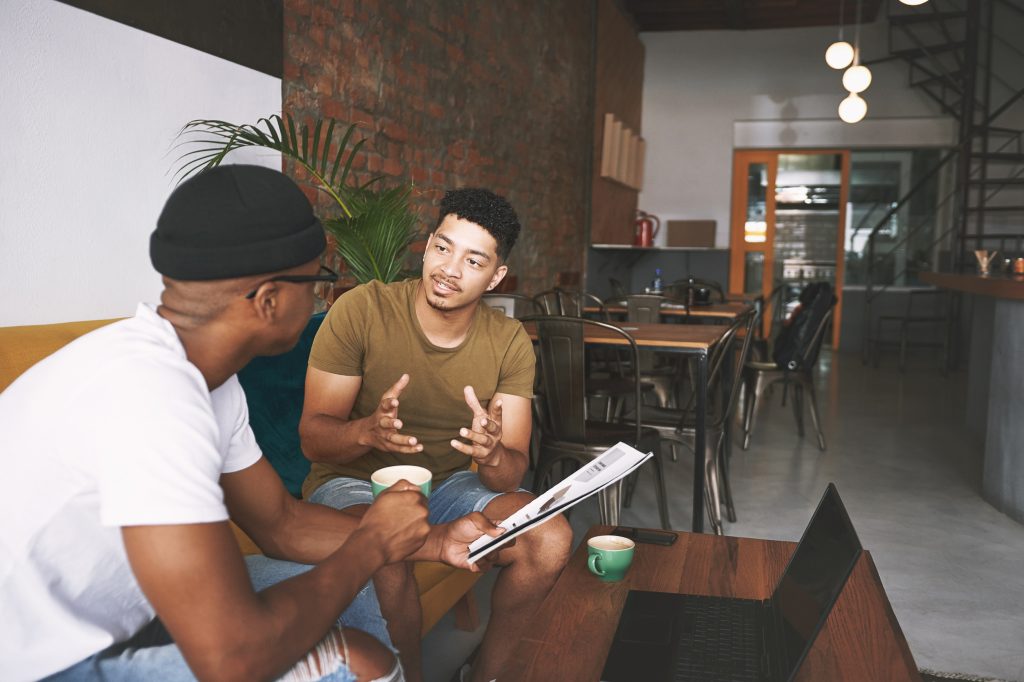 Two young men discussing their relationship while sitting together in a coffee shop