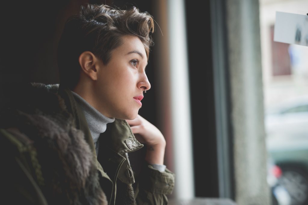 Young adult looking through the window and they think