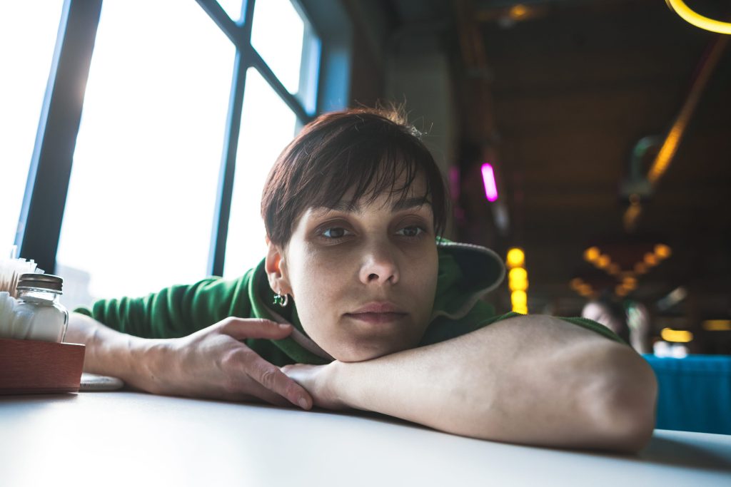 woman sitting at a cafe overthinking feelings of shame 