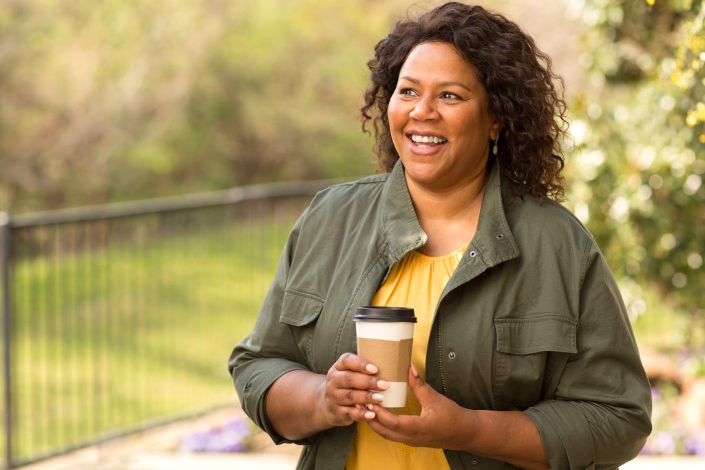 Black woman smiling and laughing as she embraces a slow moment in life. 