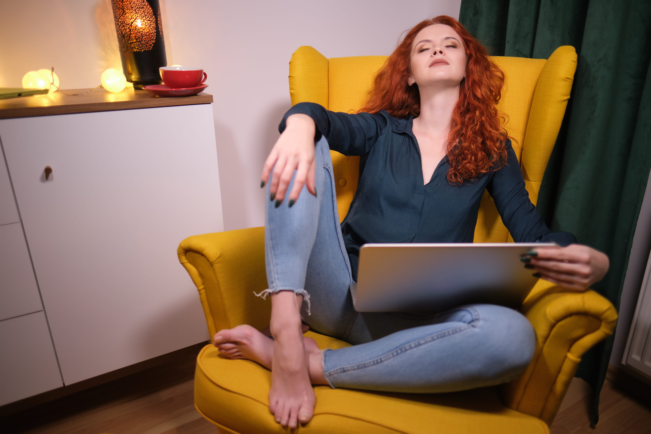 Woman with red curly hair holding computer and thinking 