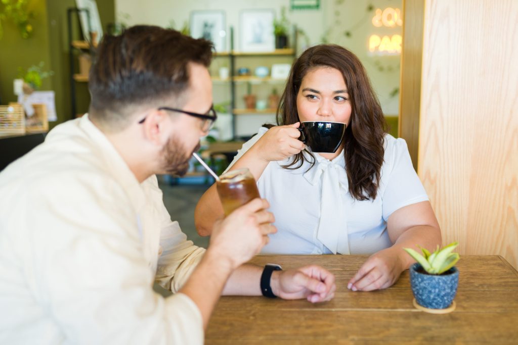 Woman drinking coffee with her boyfriend during a date at a cafe